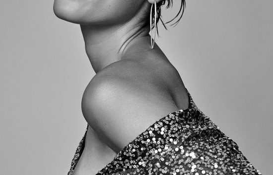 Fashion shot of a woman in a studio with grey background.