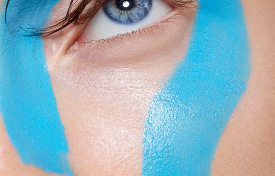 Closeup of woman's face with blu paint makeup